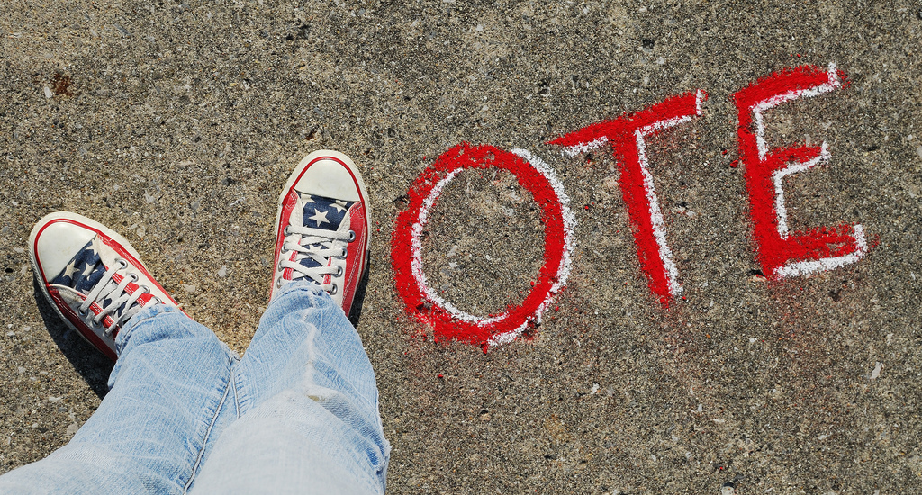 Vote written on road with person's shoes forming the V